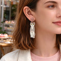 Grey acrylic cat dangle earring with gold hook and yellow-eyed cartoon cat face