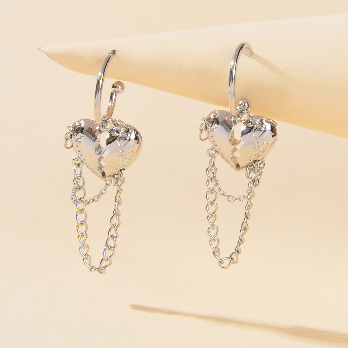 Pair of silver hoop heart charm earrings with dangling chain tassels
