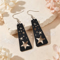 Black starry sky dangle earrings with cutout moon and star symbols, gold-tone hooks