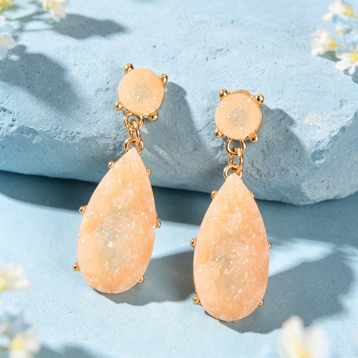 Gold-tone teardrop dangle earrings with two peach faux gemstone drops on flat pad.