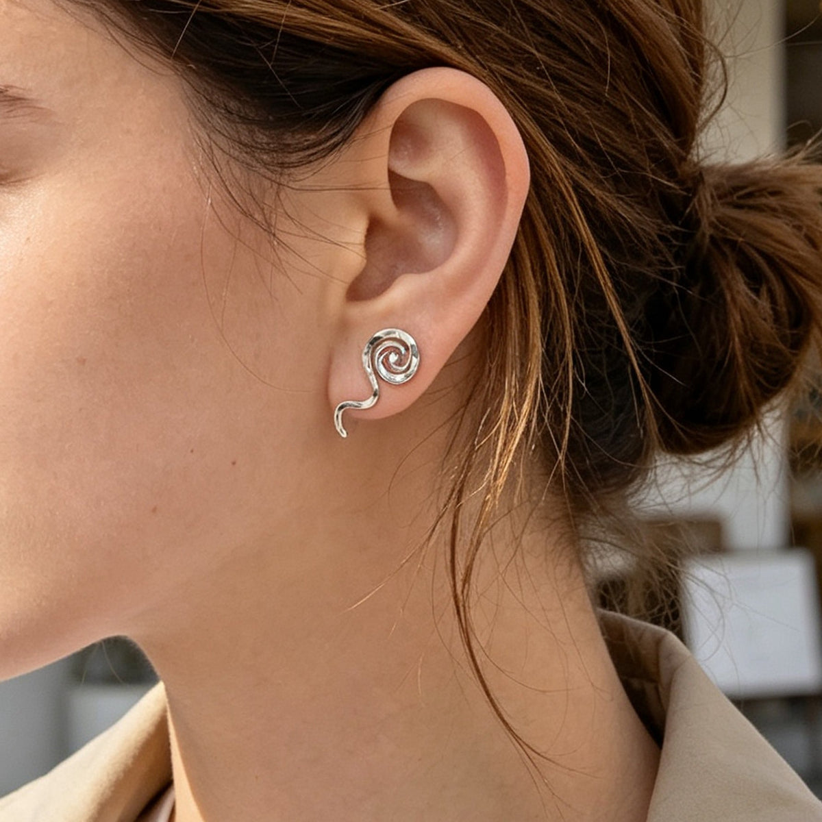 Silver spiral no-piercing ear cuff on model's ear, curved clip back