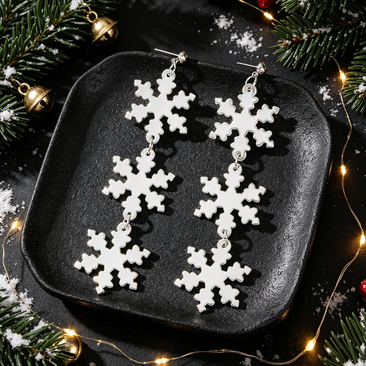 Silver snowflake dangle earrings with clustered snowflake charms on display plate