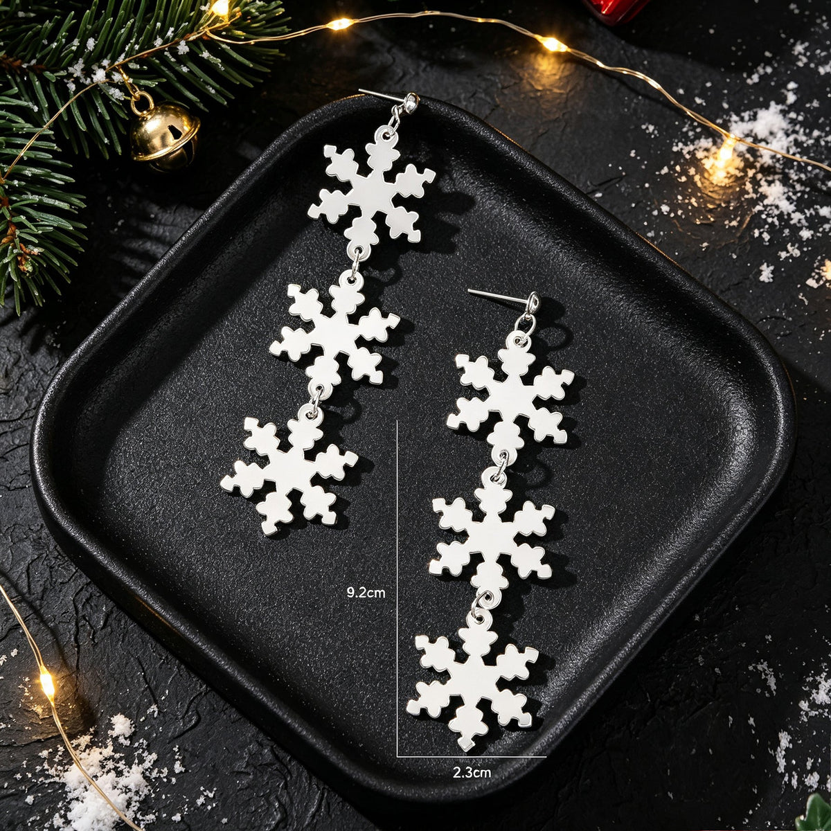 Silver snowflake long dangle earrings with measurement guide on black tray