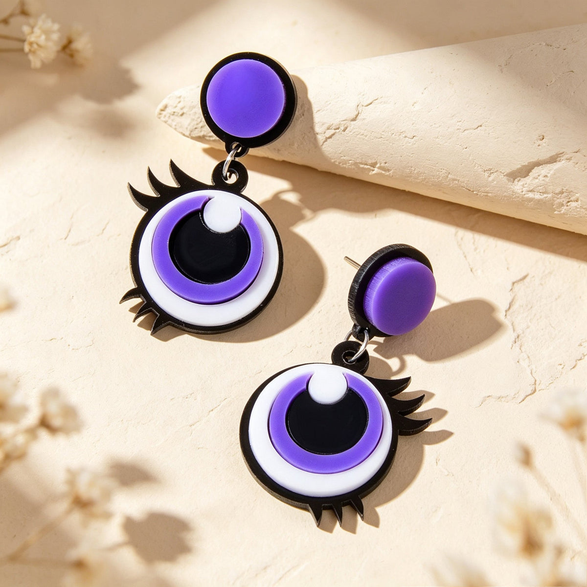Purple and black cartoon eye dangle earrings with round eye face and spiky starburst edge