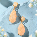 Gold-tone dangle earrings with peach teardrop faux gemstones and small round tops.