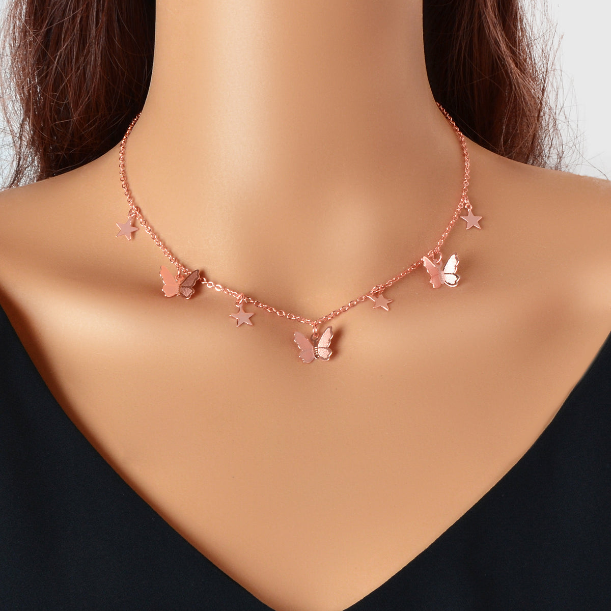 Rose-gold tone collar necklace with star and butterfly charms, short neckline fit