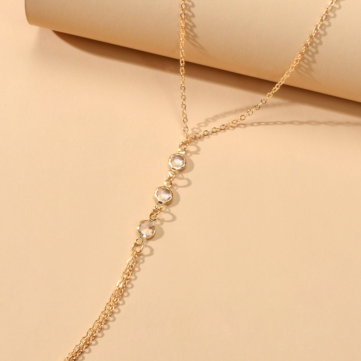 Gold-tone body chain detail with small circular charms along a thin chain