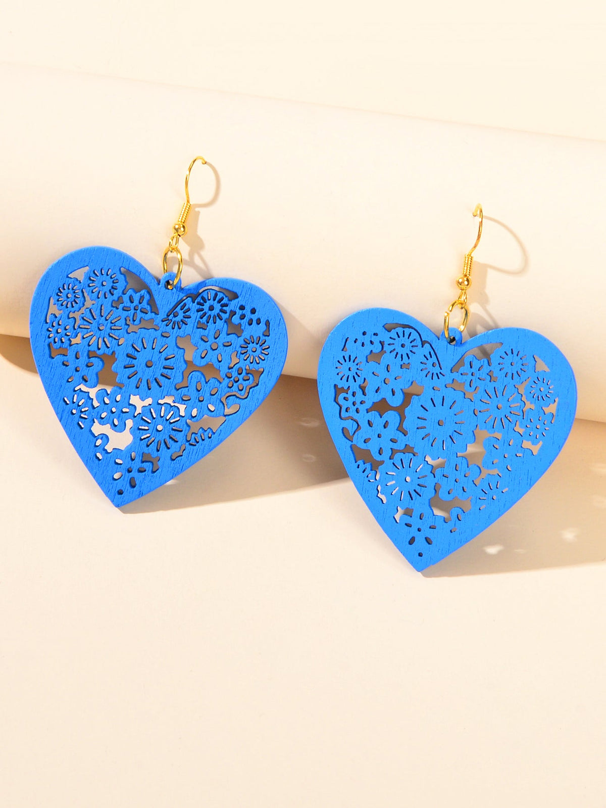 Blue heart dangle earrings with floral cutout pattern and gold hooks