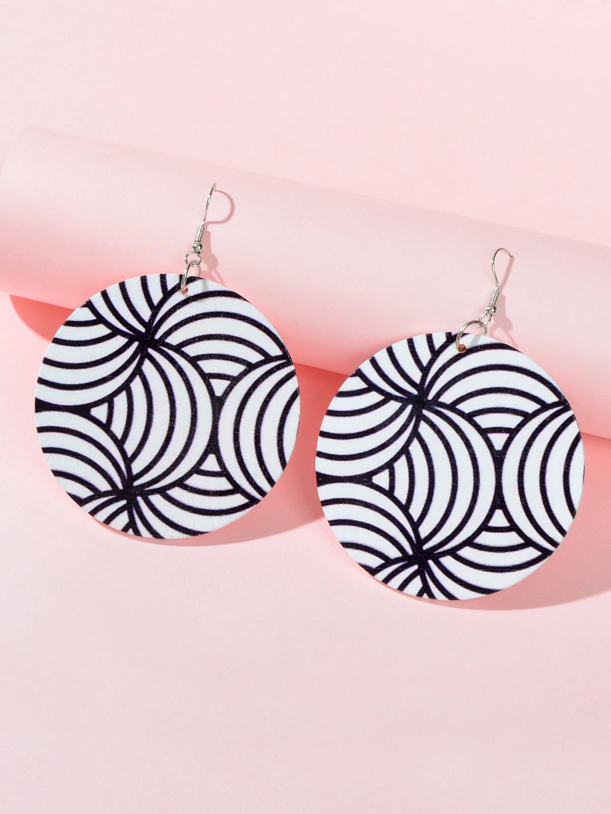 Two round zebra swirl drop earrings, black and white, hanging on silver hooks