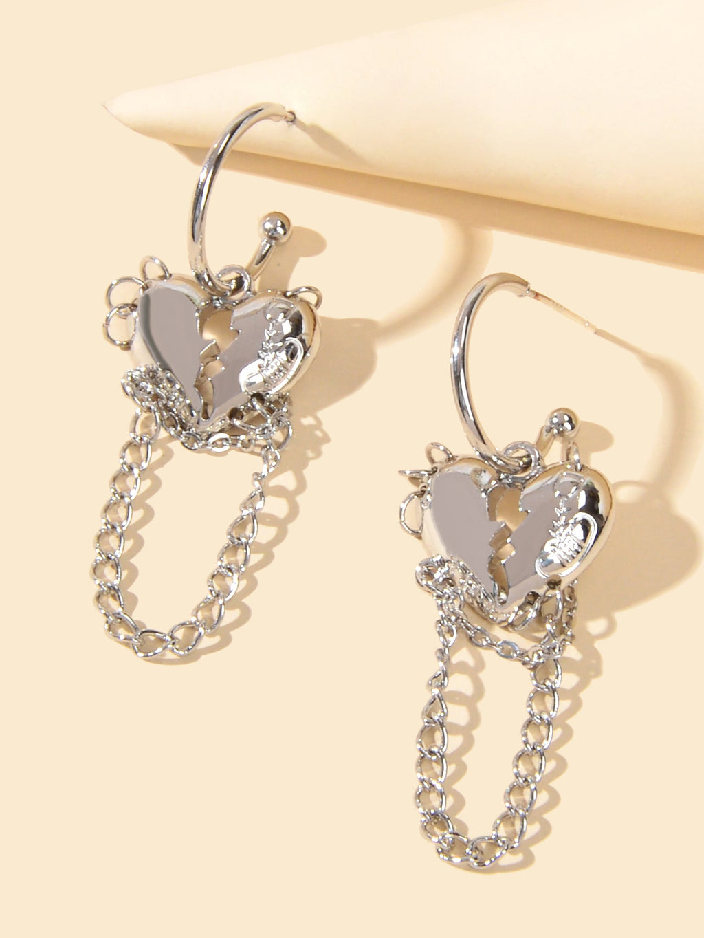 Silver hoop earrings with layered heart charms and dangling chain links
