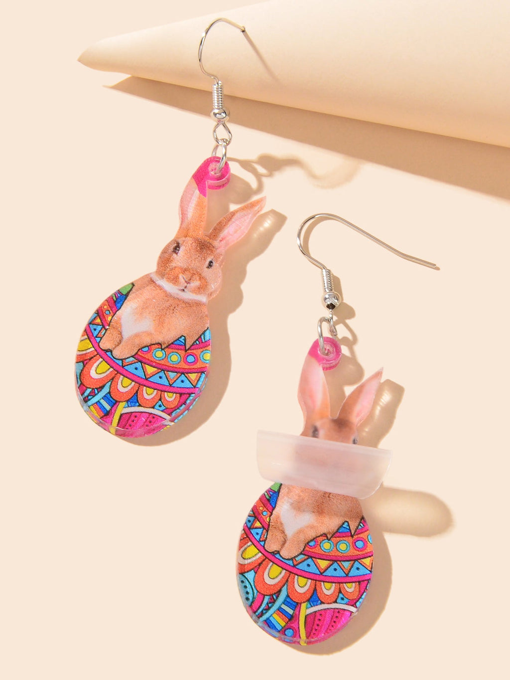 Pair of dangling bunny charm earrings showing multicolor egg-pattern bodies