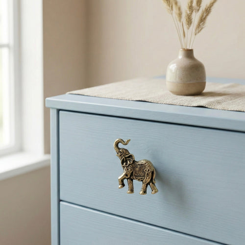 Antique brass elephant drawer knob on a light blue cabinet drawer front