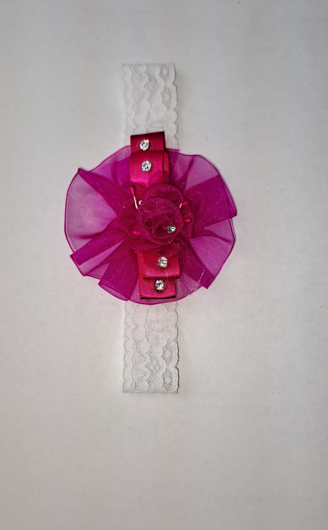 Fuchsia ruffle flower baby headband with organza bow and rhinestone accents on white lace