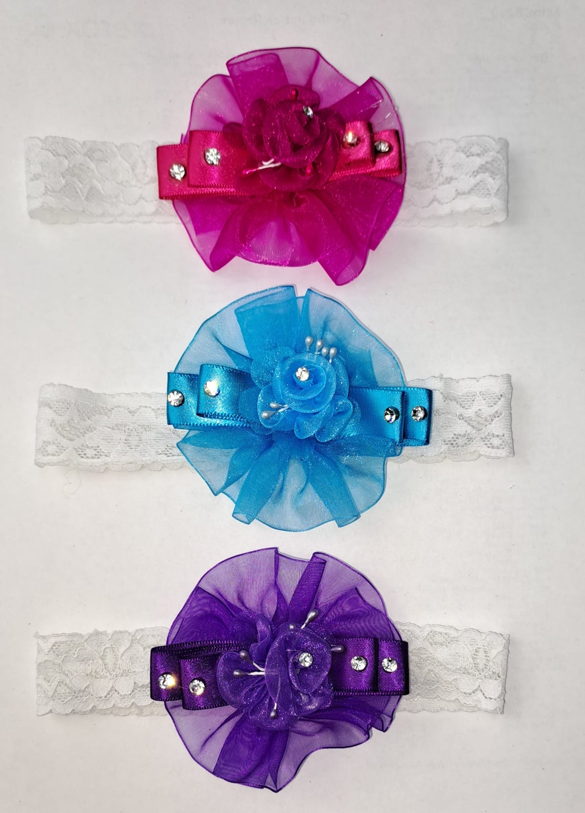 Set of three baby girl headbands in purple, fuchsia, and blue with rhinestone flowers