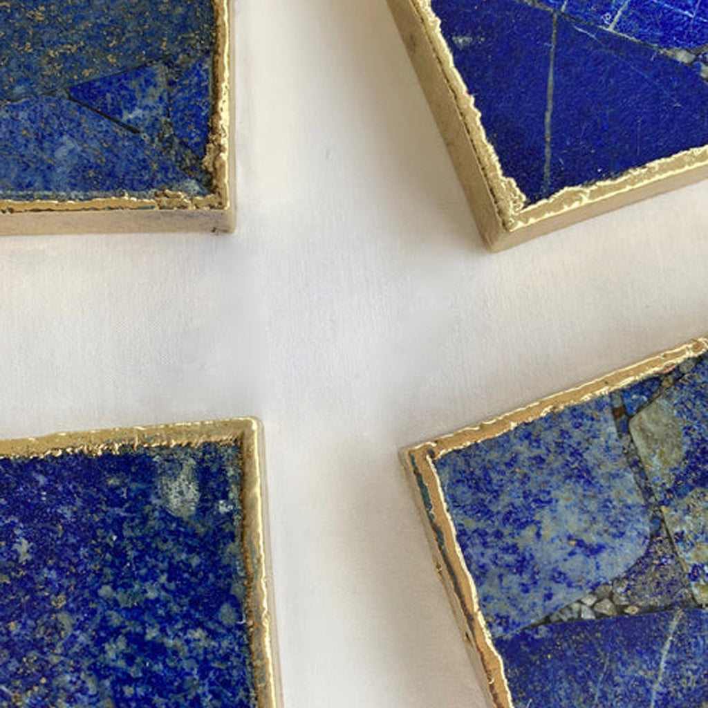 Corner close-up of square lapis blue coasters with gold-toned beveled trim