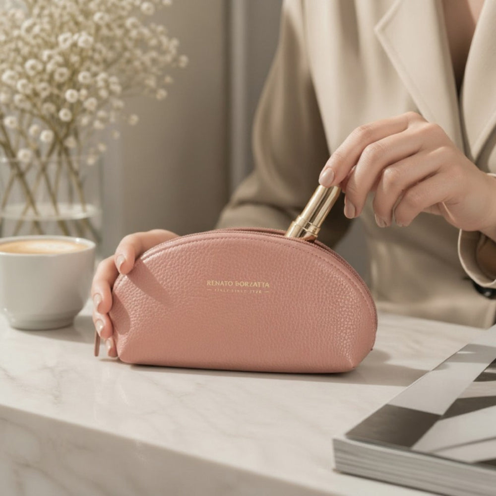 Antique pink half-moon leather pencil case on desk, hand holding pen