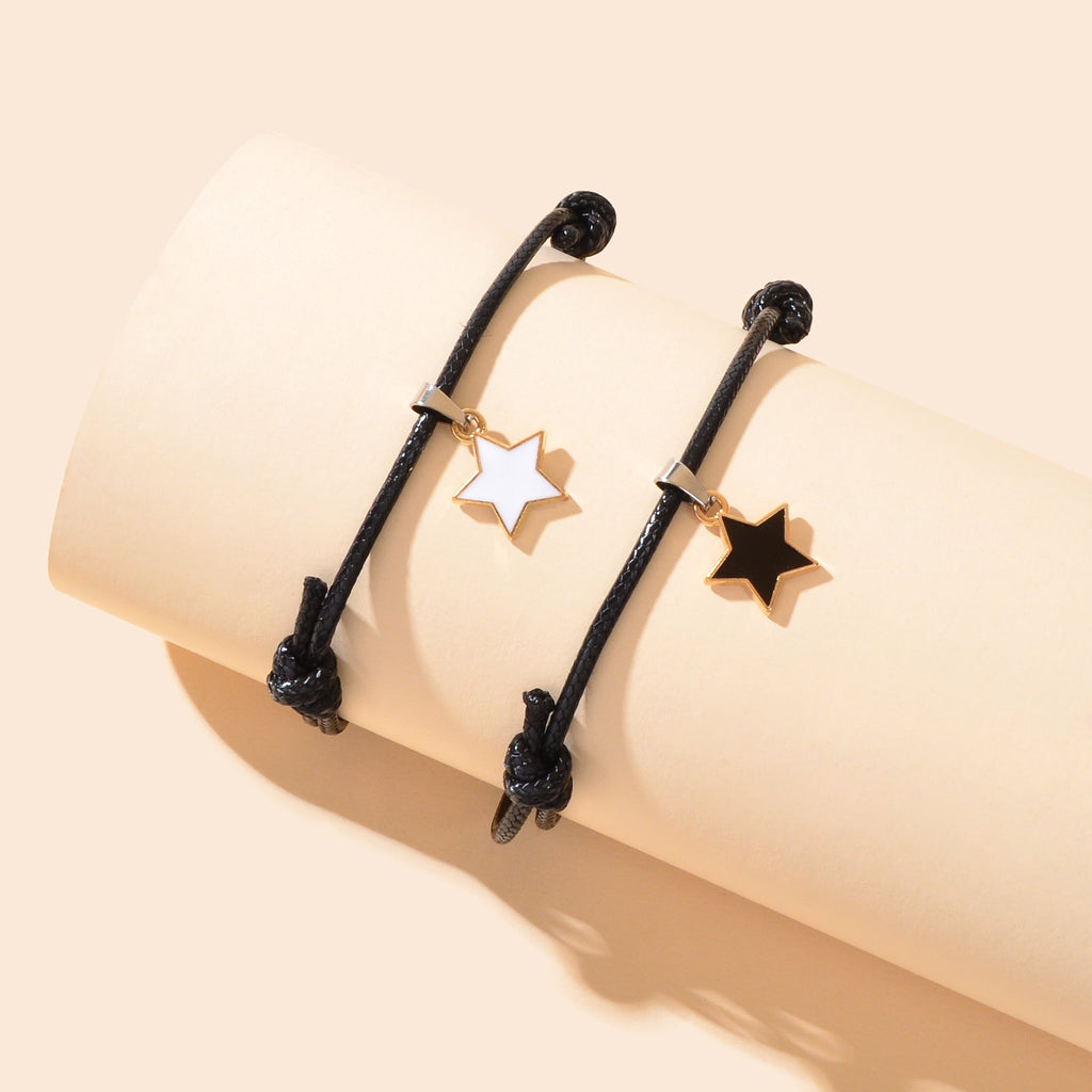 Two black rope bracelets with gold star charms, adjustable sliding knots