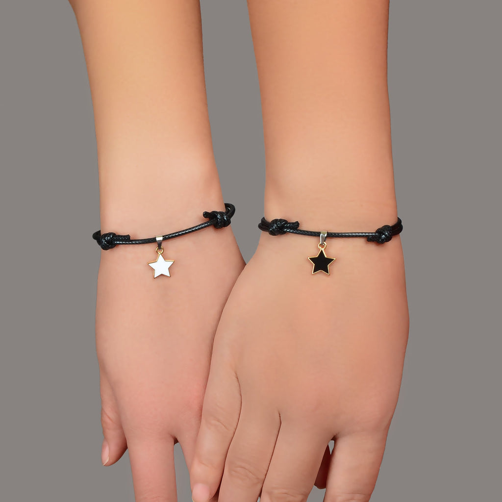Black rope bracelets on wrists with gold star charms, adjustable sliding knots