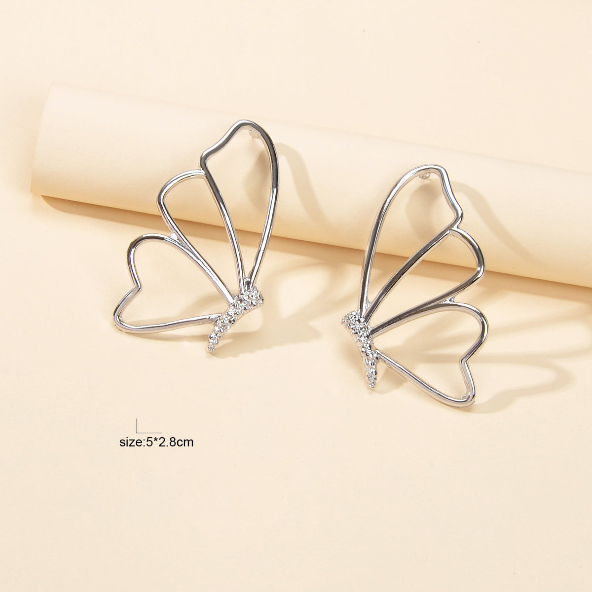 Silver butterfly stud earrings with hollow heart-like wings and rhinestone sparkle
