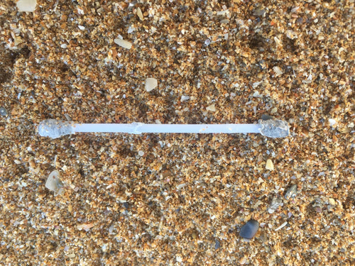 Single cotton bud with white tips on a light wooden stem