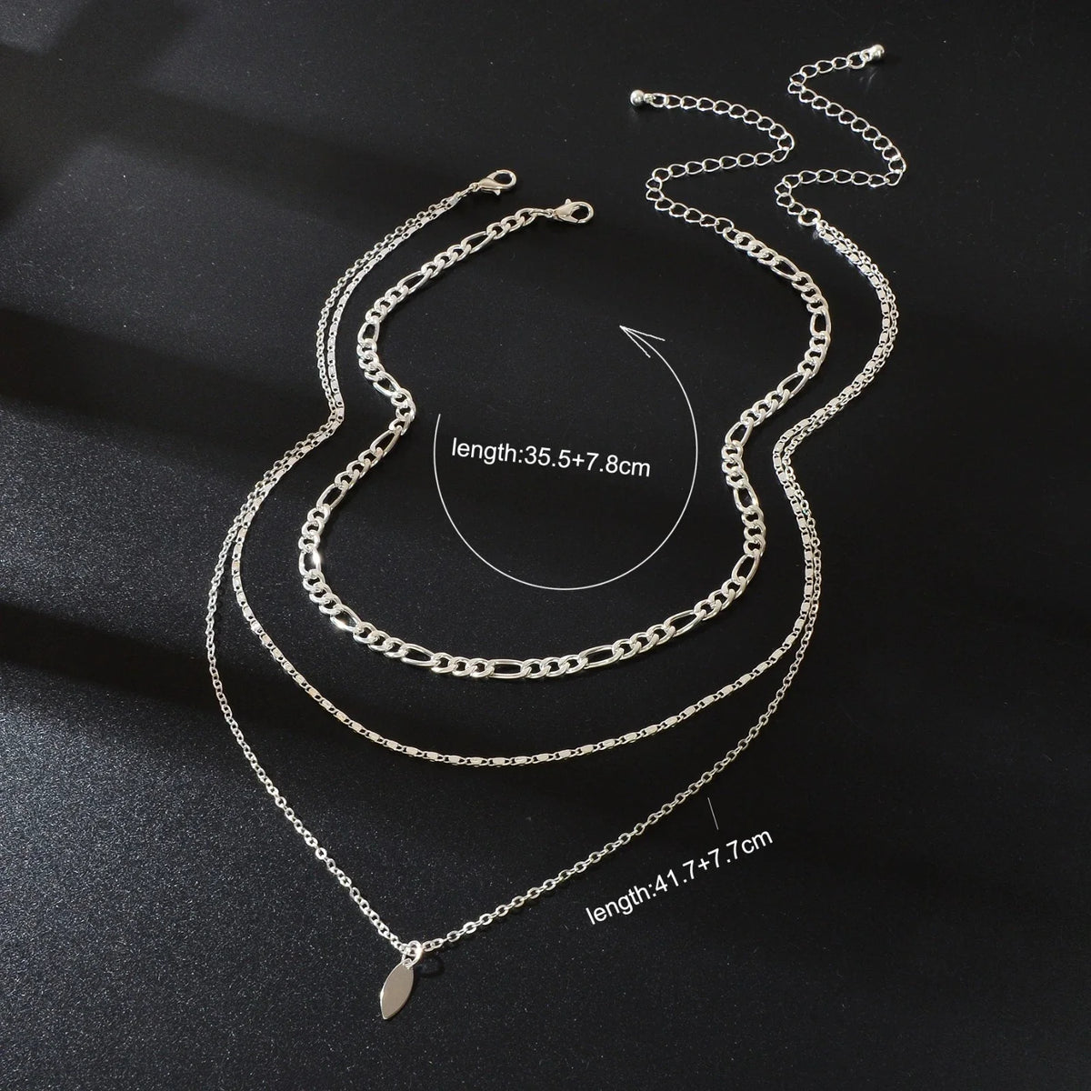 Layered silver-tone choker necklace with leaf-shaped drop charms and three chain strands