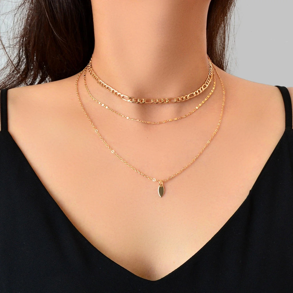 Gold-tone choker necklace with stacked chains and teardrop charm with green center
